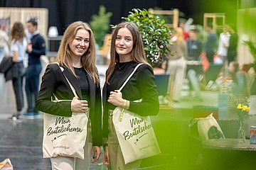 2 lächelnde junge Frauen mit Stofftaschen am Arm